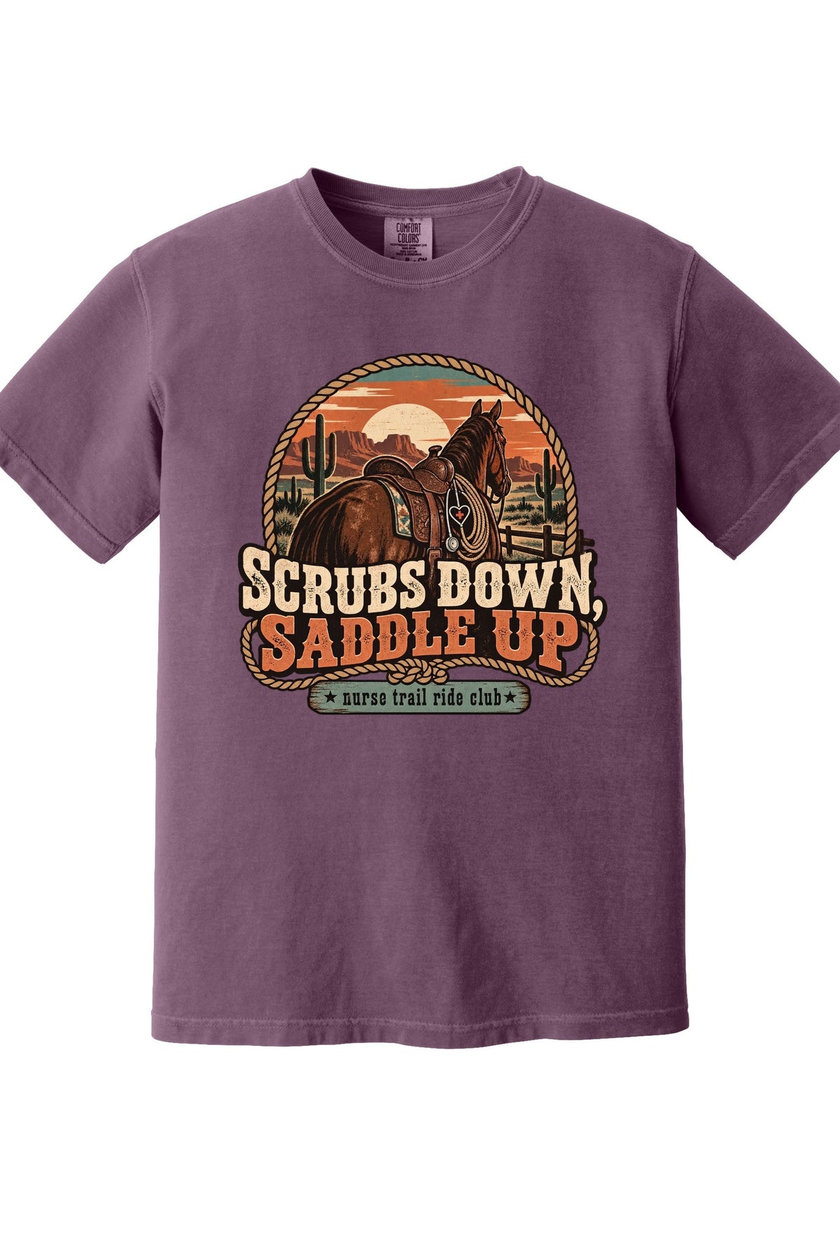 A purple short-sleeve crewneck t-shirt featuring a retro western-themed graphic of a horse rider on a trail with the text 'SCRUBS DOWN, SADDLE UP' and 'survival ride club'.