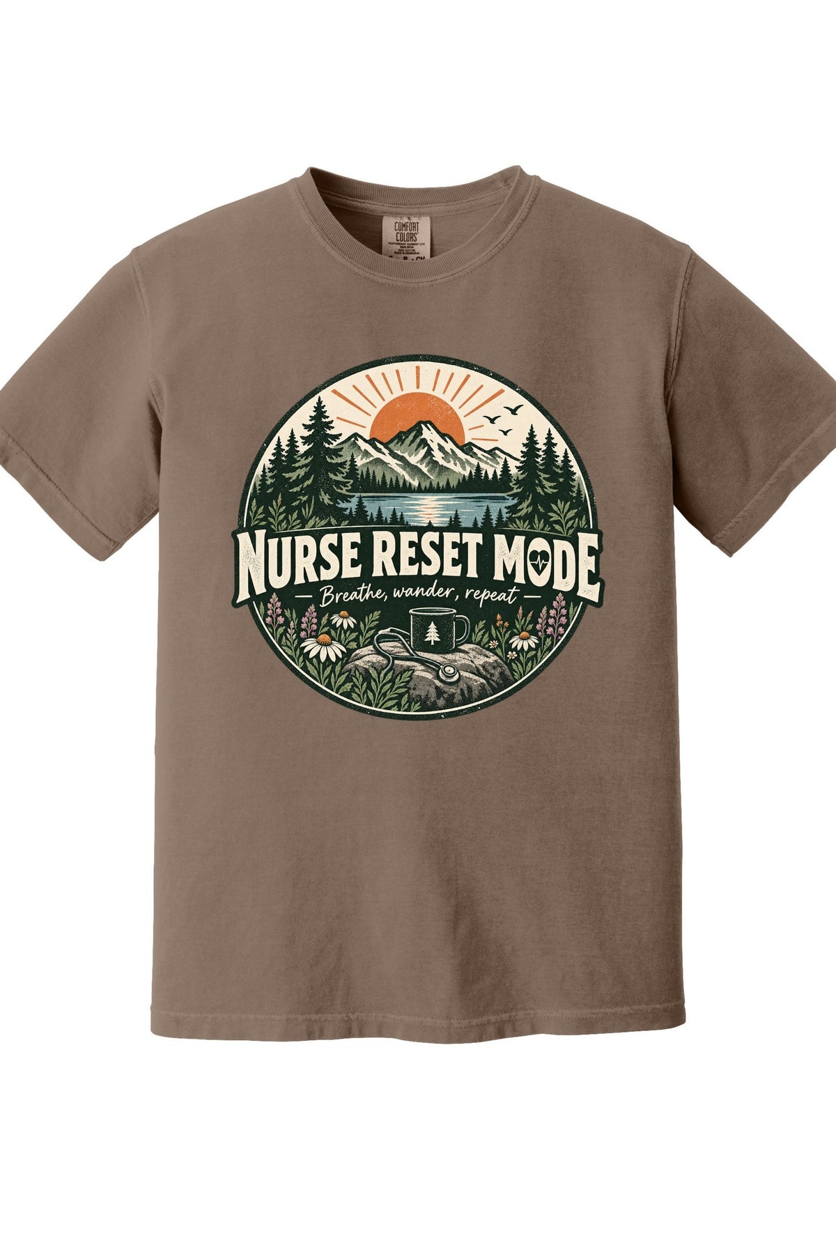 A brown short-sleeve crewneck t-shirt featuring a circular graphic on the chest with a mountain, pine trees, and the text 'NURSE RESET MODE'.