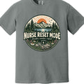 A heather gray short-sleeve crewneck t-shirt featuring a circular graphic on the chest with a mountain, pine trees, and a sunrise, with the text 'NURSE RESET MODE' and 'Breathe, wonder, repeat'.